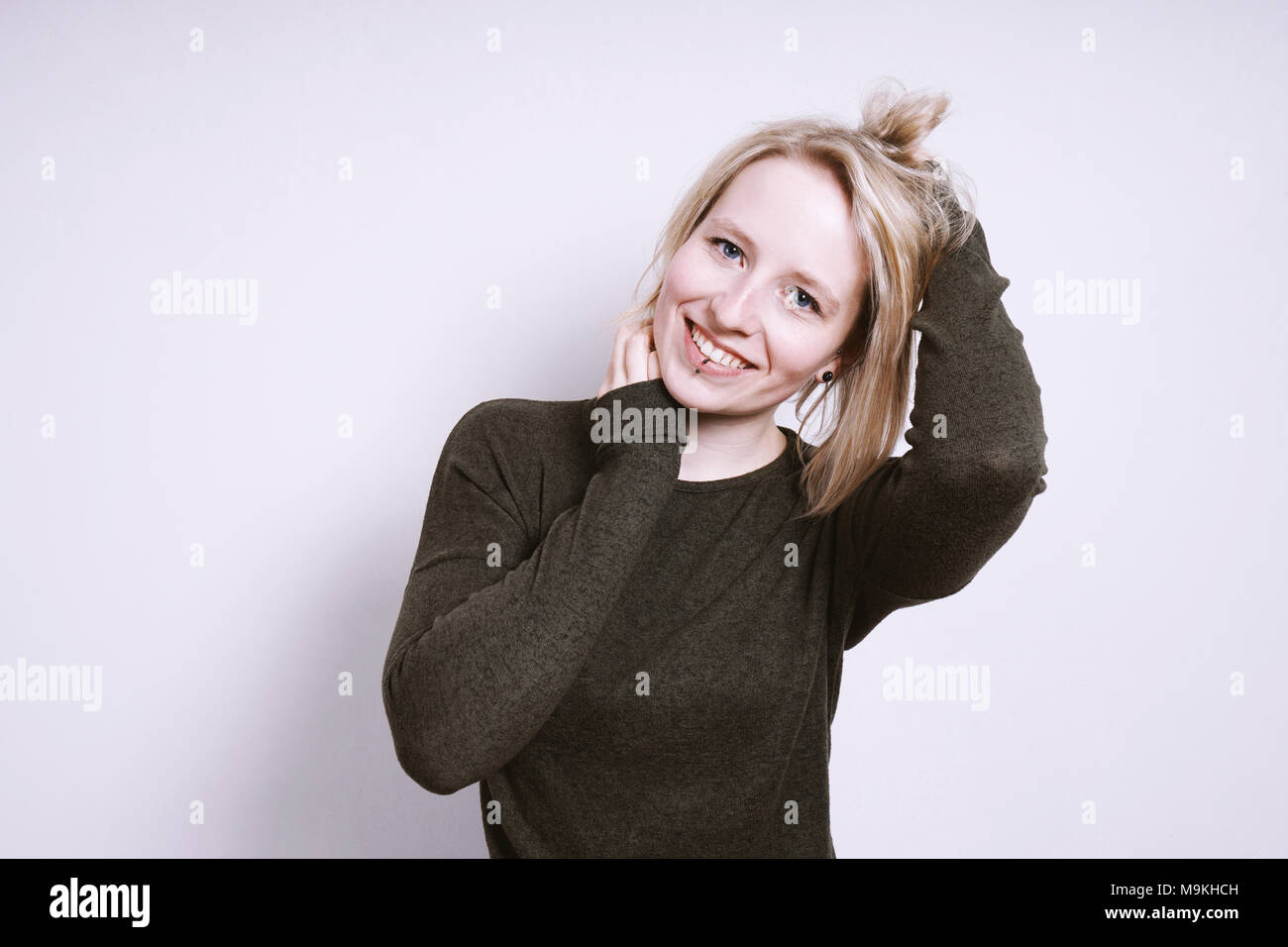 happy young woman smiling with hands in hair Stock Photo