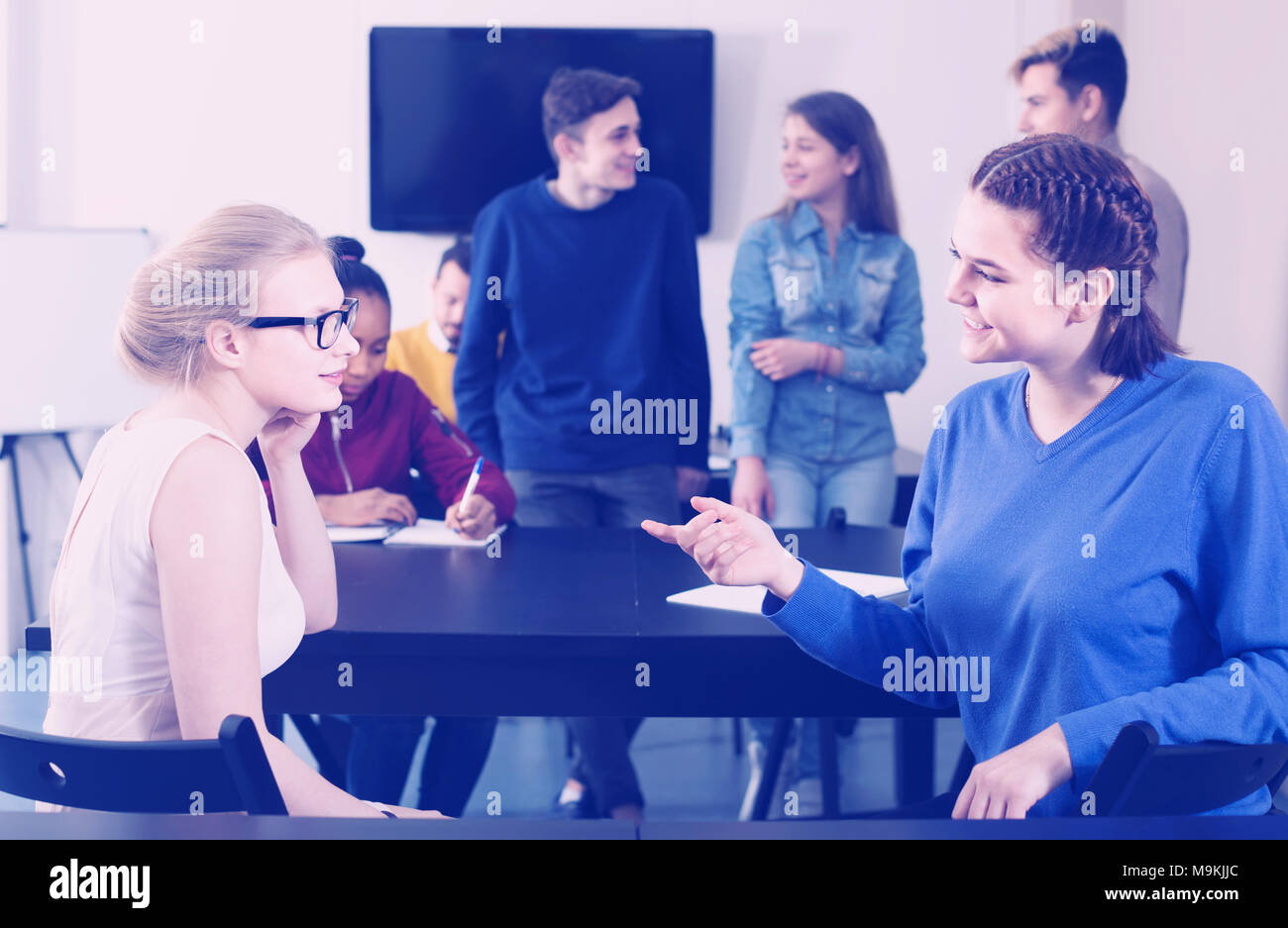 interested classmates having animated talks at break between classes ...