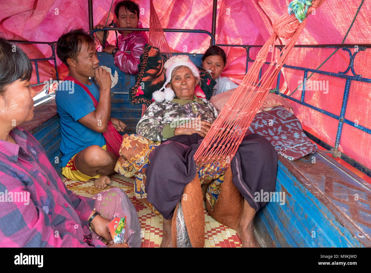 A family travels home in a trailer attached to the back of a tractor after visiting a spiritual healer. Pekhon Jetty, Kayan State, Myanmar. Stock Photo
