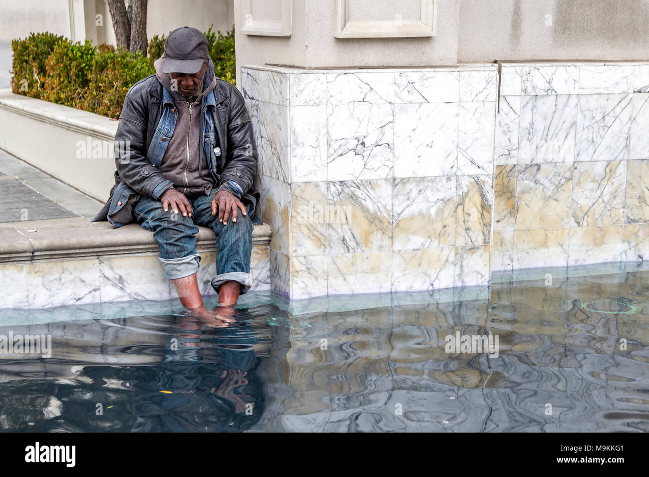 Man cooling his feet in one of the fountains at  Caesars Palace,  Las Vegas, Navarda, U.S.A. Stock Photo