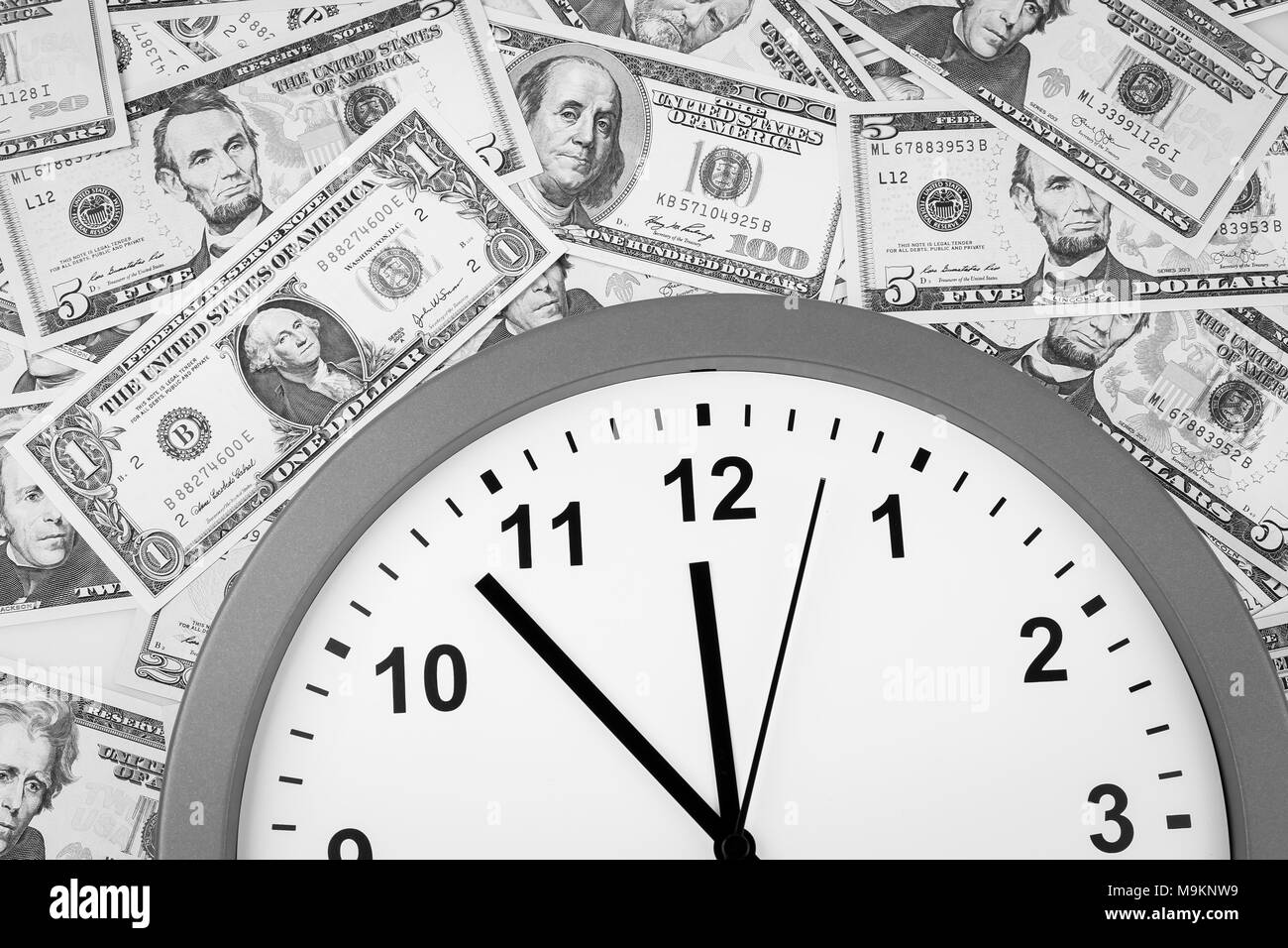 Clock on assorted American banknotes. Time is money idea Stock Photo