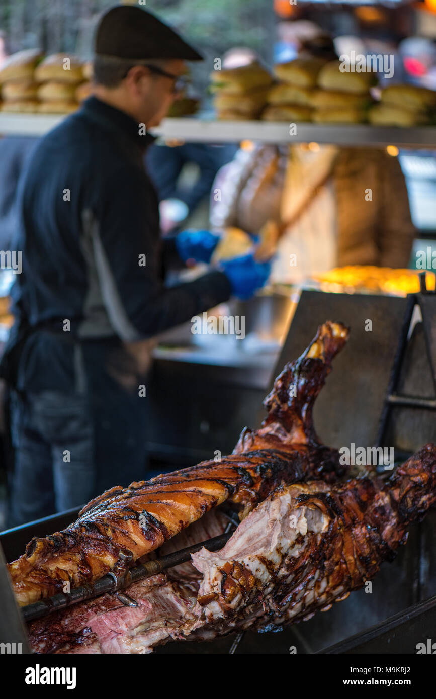 Astreet food stall at borough market in central london selling hog roast pig or pork on a spit or rotisserie. Freshly cooked pulled pork meat on sale. Stock Photo