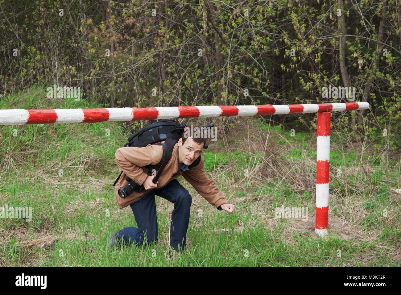 A young man with a backpack passes under the barrier Stock Photo