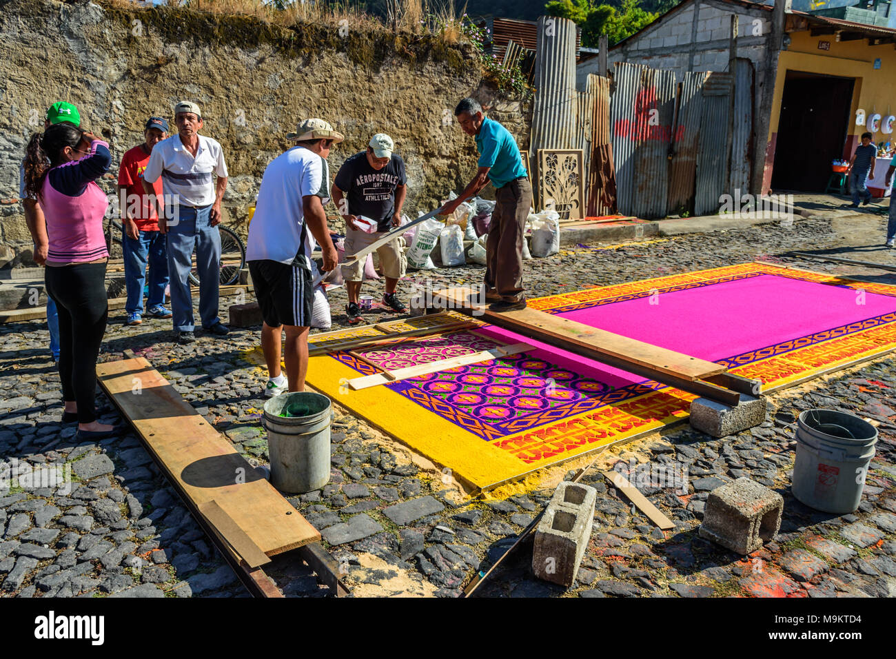 Antigua, Guatemala -  March 6, 2016: Locals make dyed sawdust Lent procession carpet with stencils in town with famous Holy Week celebrations Stock Photo