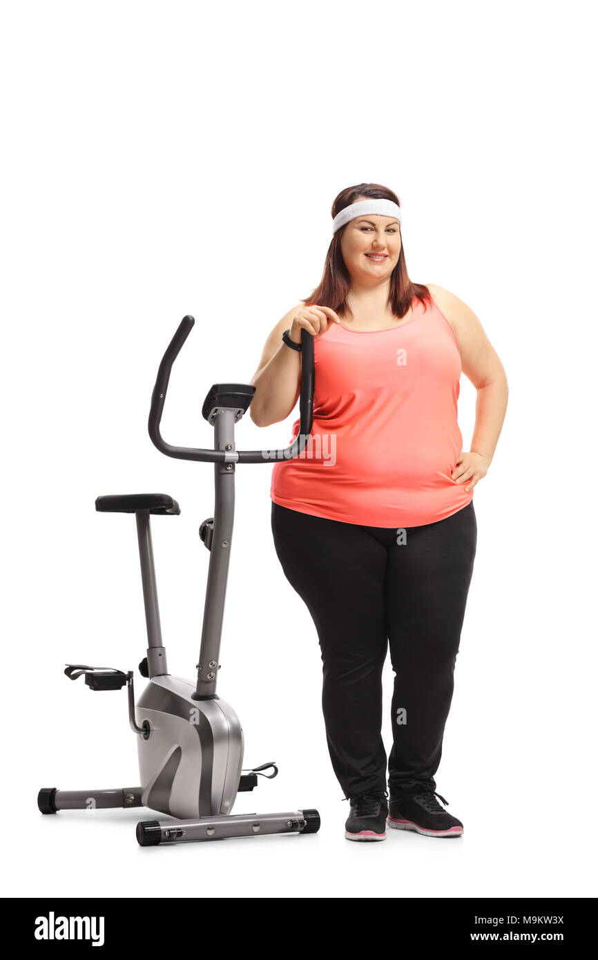Full length portrait of an overweight woman leaning on a stationary bike isolated on white background Stock Photo