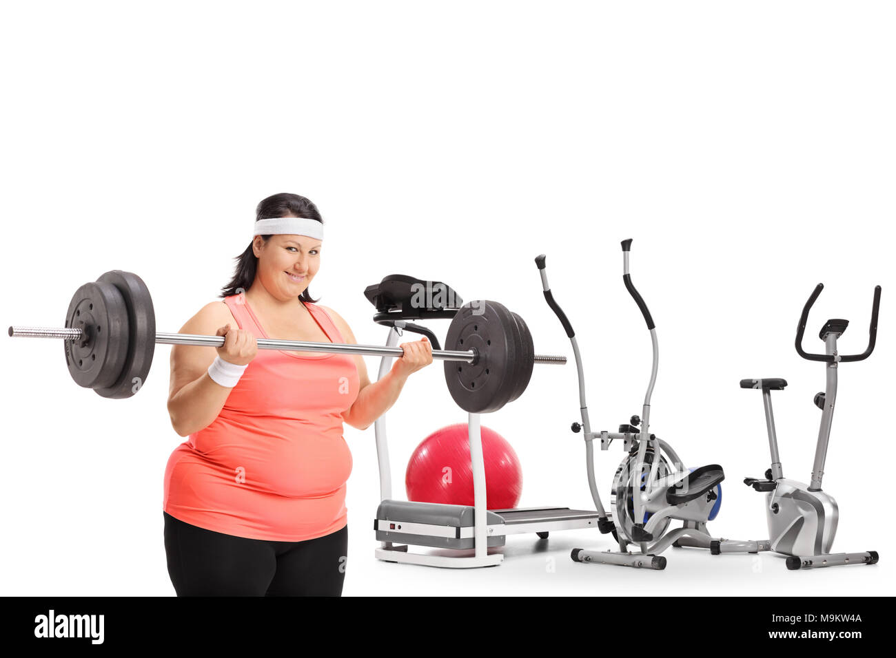 Overweight woman lifting a barbell in front of exercise machines