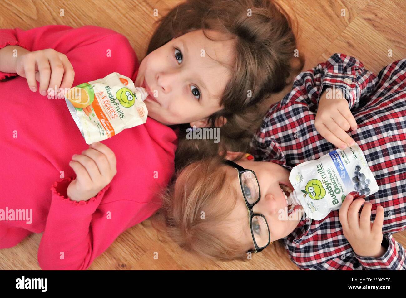 Sisters enjoying Buddy Fruits in the kitchen Stock Photo