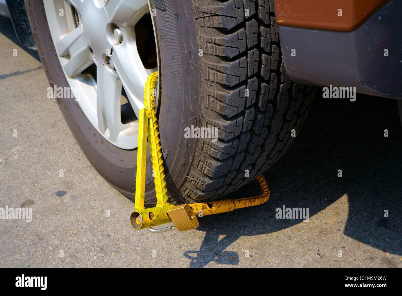 Car wheel blocked by wheel lock because illegal parking violation Stock