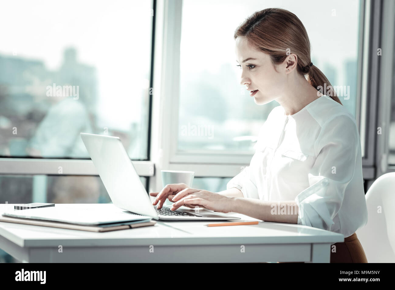 Concentrated busy woman sitting and using the laptop. Stock Photo