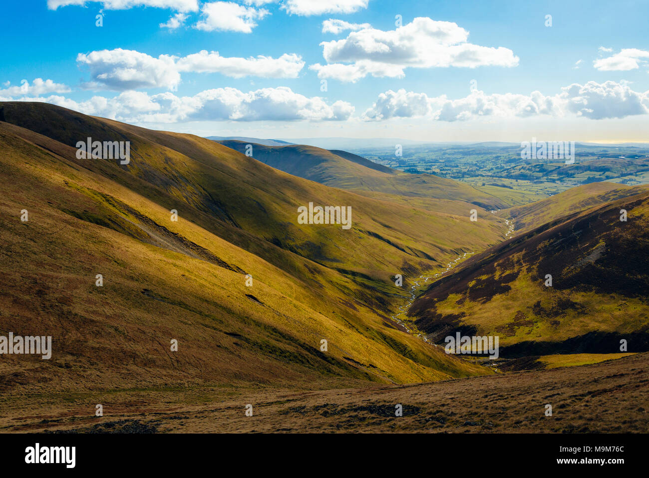 View down Long Rigg Beck in the Howgill Fells in the Yorkshire Dales National Park, England, to the Lune valley and the M6 motorway Stock Photo