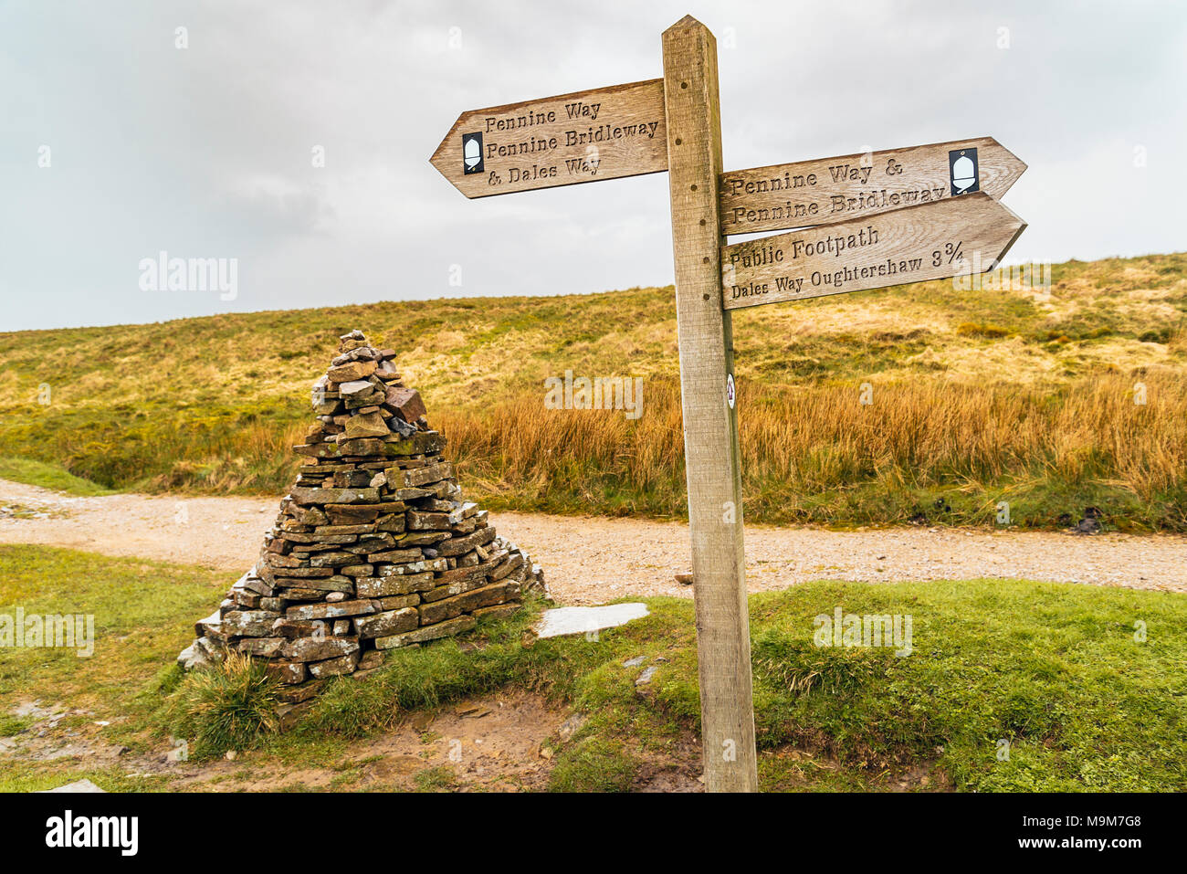 Direction sign and cairn at intersection of several walking and biking routes on the Cam High Road between Ribblesdale and Langstrothdale, Yorkshire Stock Photo