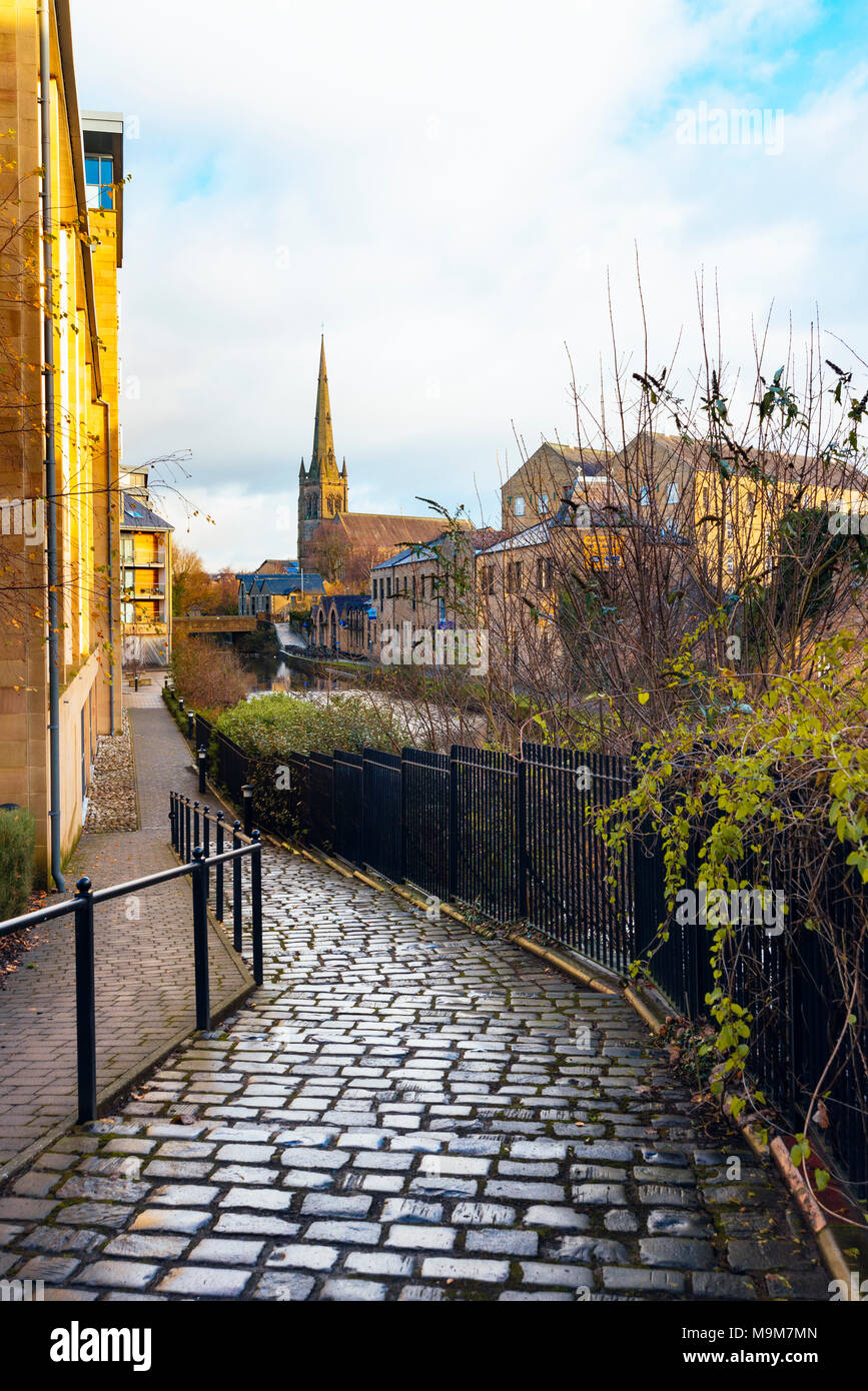 Path passing new housing beside the Lancaster Canal in Lancaster England, looking towards the White Cross pub and Saint Peter’s RC Cathedral Stock Photo
