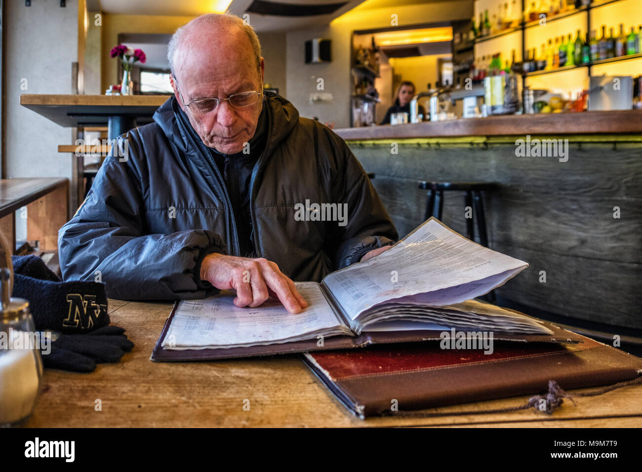 Berlin-Mitte. Keyser Soze bar and restaurant interior with senior elderly man reading a menu Stock Photo
