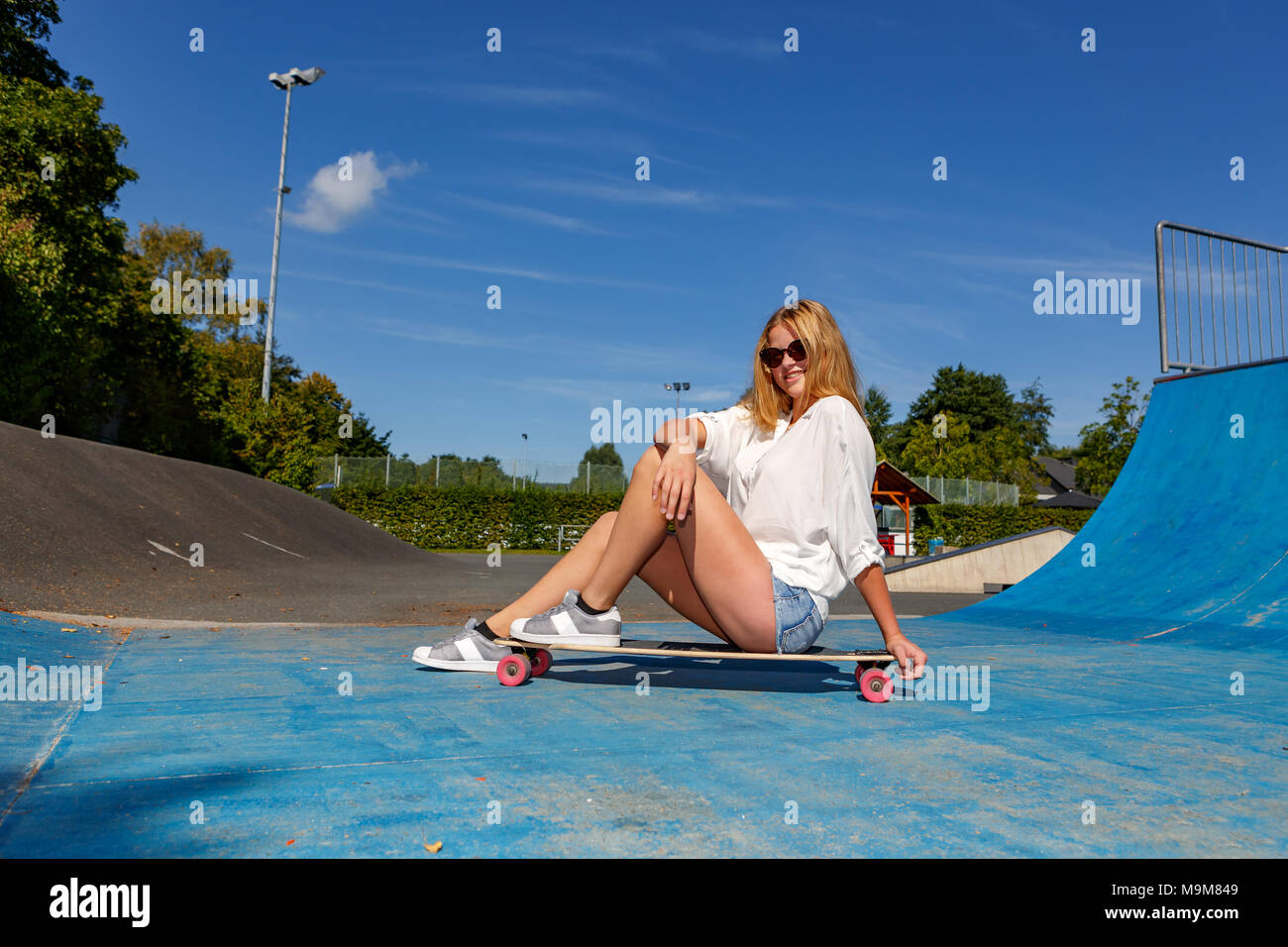 a teenage girl with a skateboard on halfpipe in the park Stock Photo