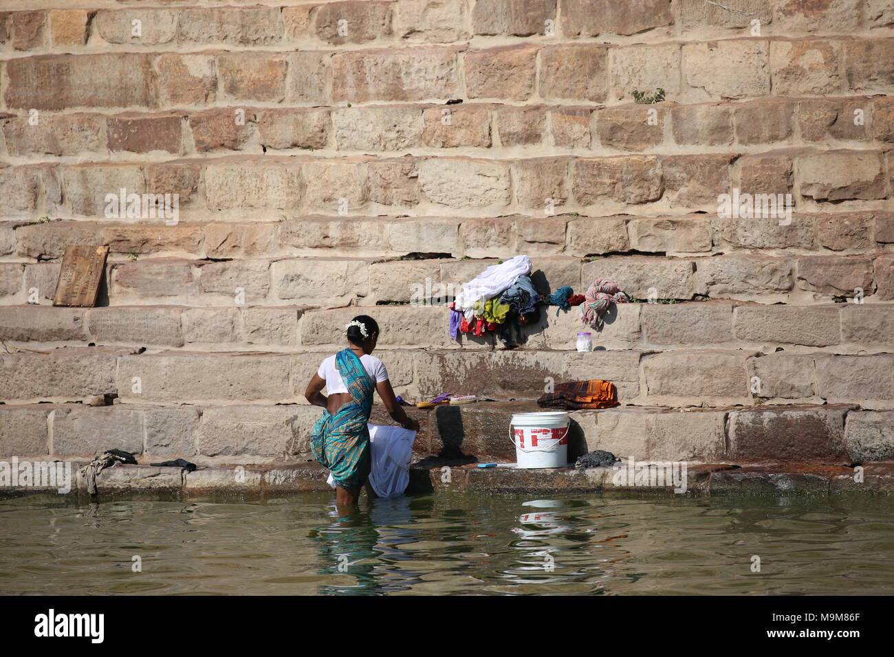 Indian woman washing clothes and dishes on the river - inderin beim waschen von Kleidung und geschirr am fluss Stock Photo