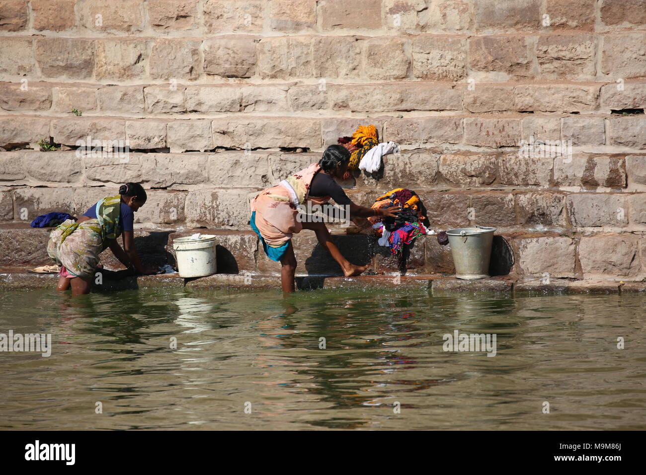 Indian woman washing clothes and dishes on the river - inderin beim waschen von Kleidung und geschirr am fluss Stock Photo