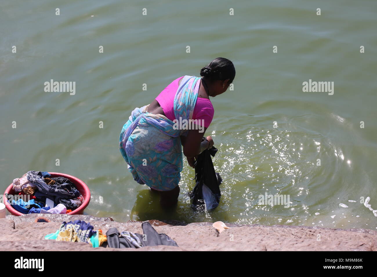 Indian woman washing clothes and dishes on the river - inderin beim waschen von Kleidung und geschirr am fluss Stock Photo