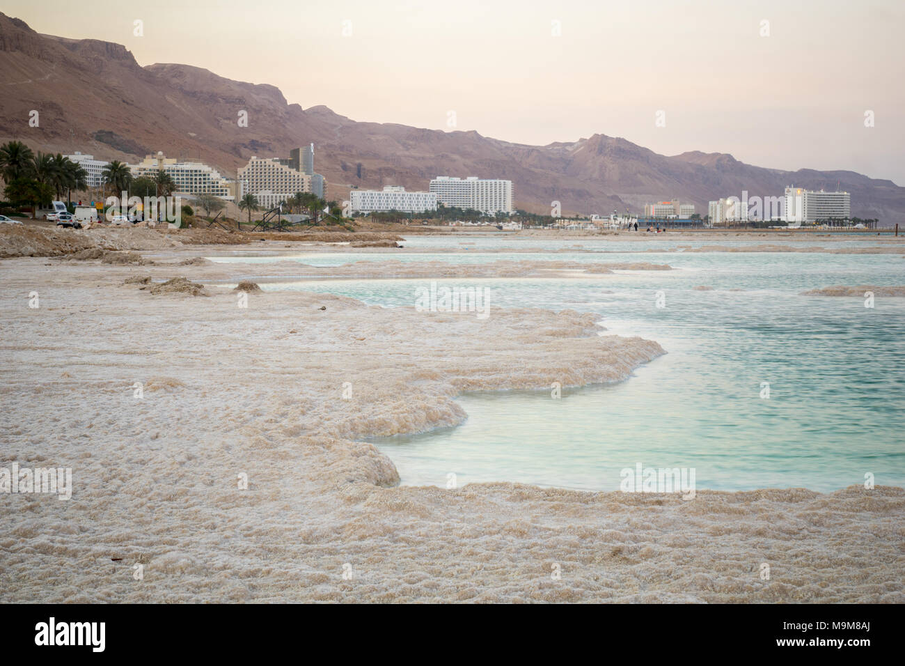 EIN BOKEK, ISRAEL - MARCH 16, 2018: Sunset view of salt formations in the Dead Sea, Ein Bokek resort, and visitors. Southern Israel Stock Photo