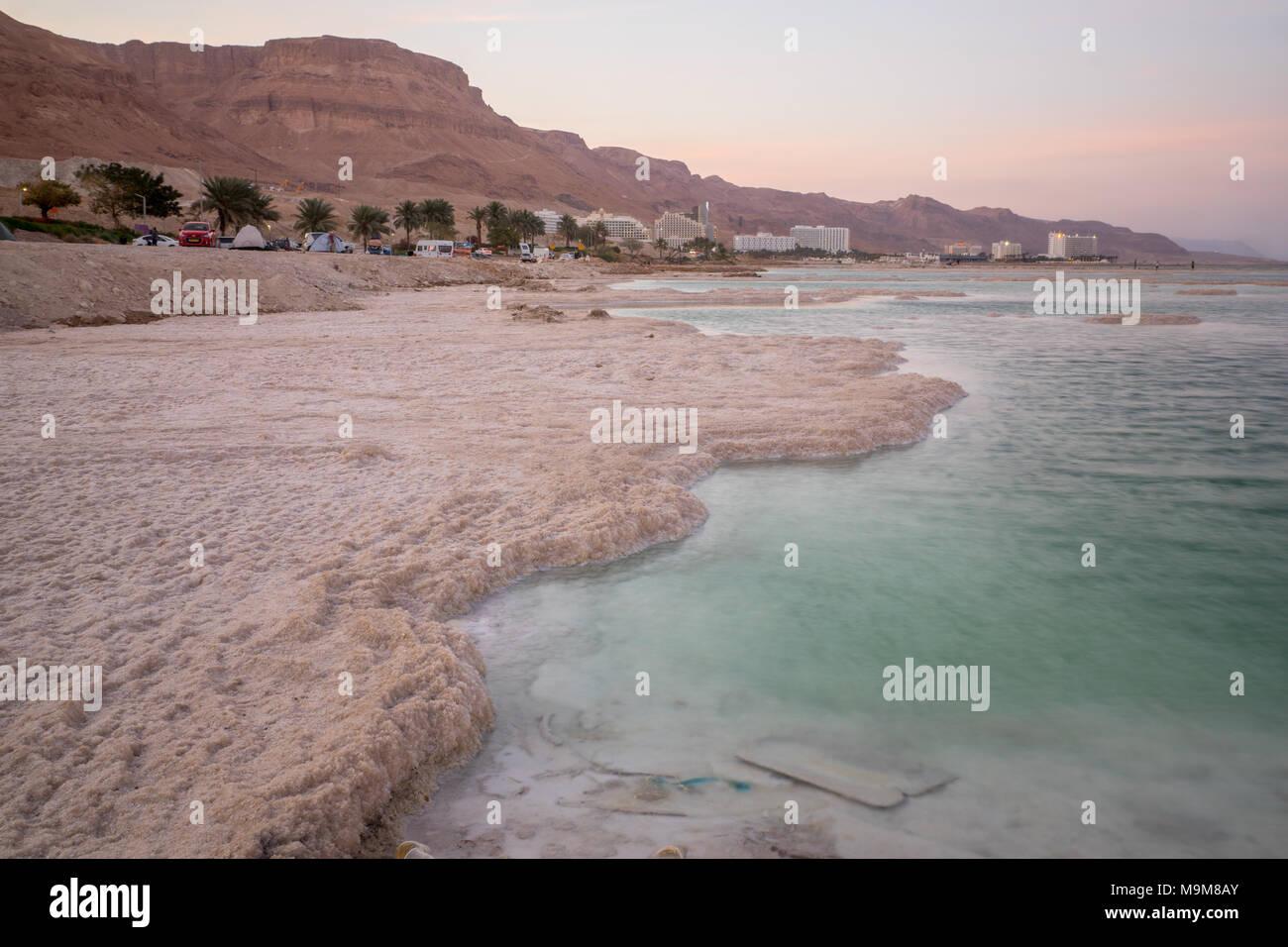 EIN BOKEK, ISRAEL - MARCH 16, 2018: Sunset view of salt formations in the Dead Sea, Ein Bokek resort, and visitors. Southern Israel Stock Photo