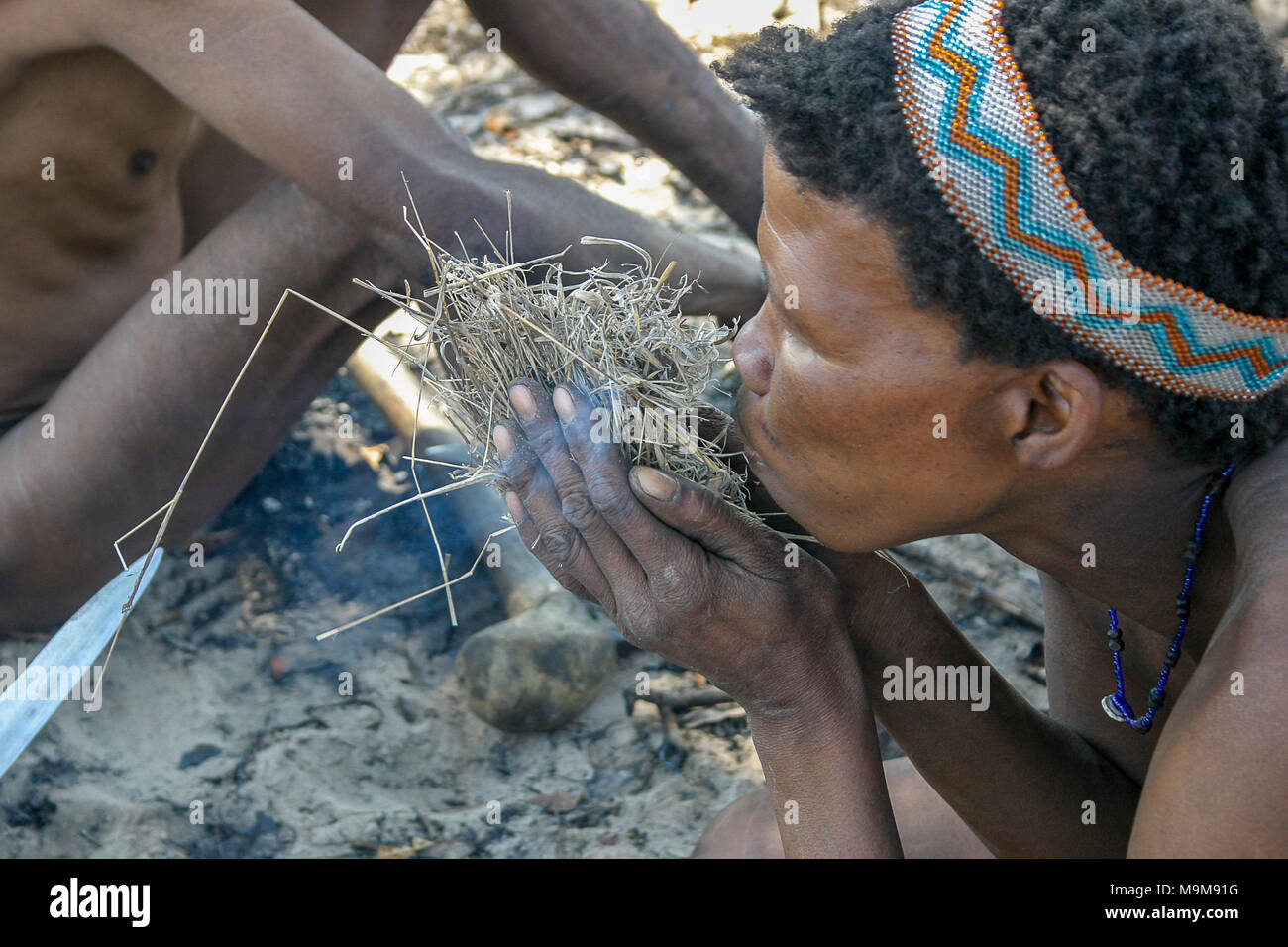 San tribe bushmen, also known as the First Tribe of Africa, making fire the traditional way in the surrounding bushland in Namibia. Stock Photo