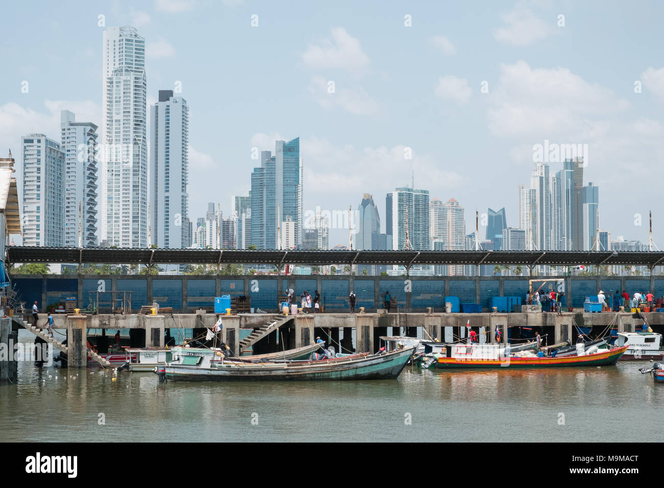 Panama City, Panama - march 2018: Fishermen and boats on fish market / harbour with city skyline, Panama City. Stock Photo