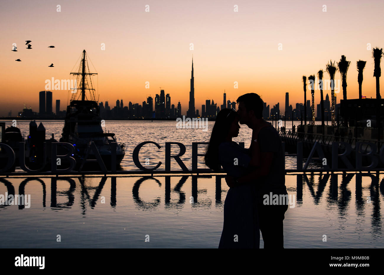 Silhouette of a romantic couple hugging at sunset in Dubai Stock Photo