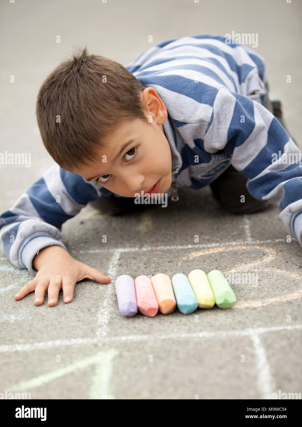 Cute little boy drawing with chalk outdoors Stock Photo - Alamy