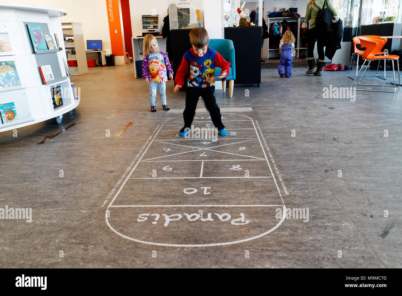 Playing hopscotch on an indoor hopscotch game in a public library in