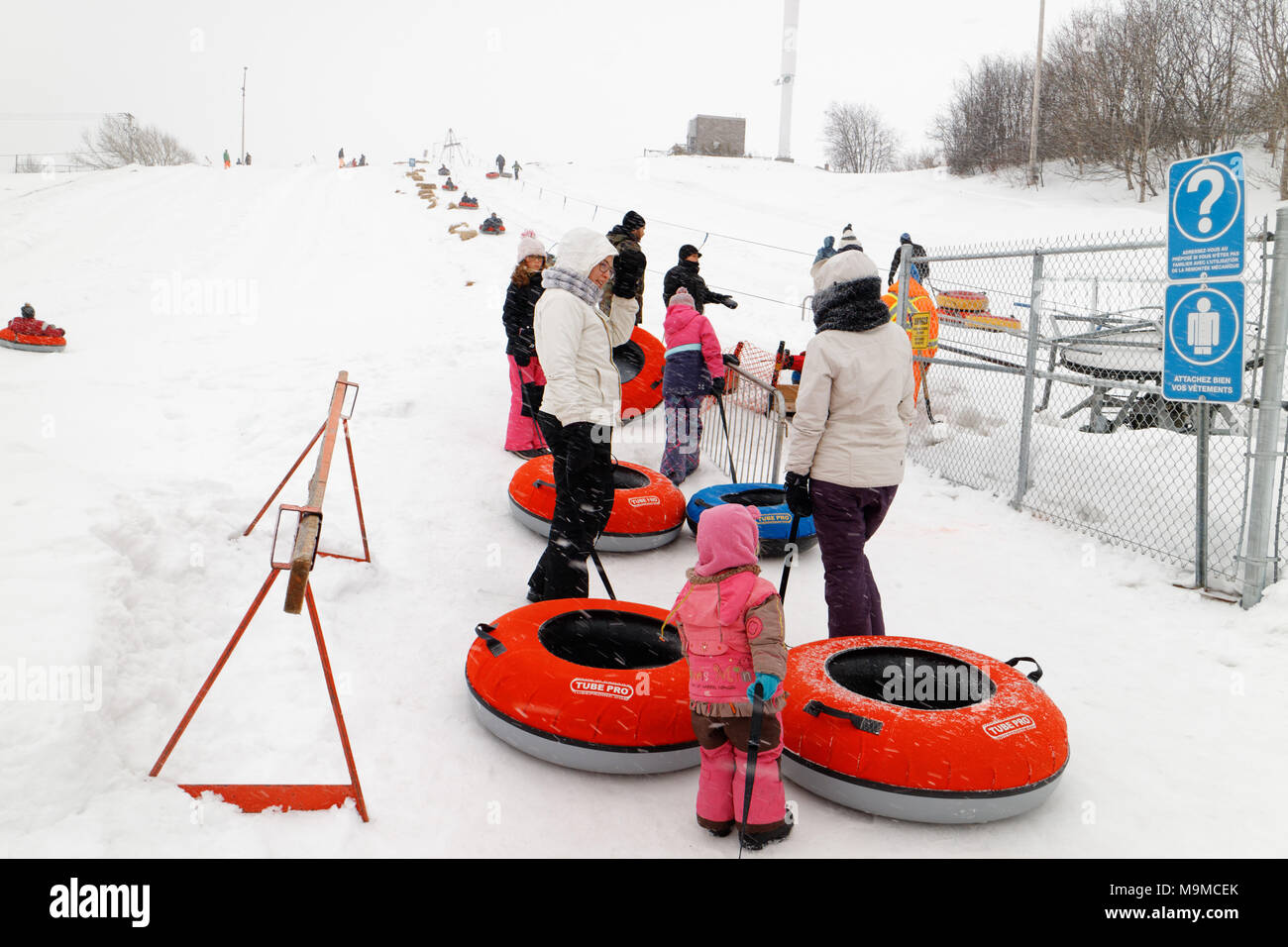 A queue of people with rubber rings waiting for the cable lift to go sliding in Rimouski Parc Beausejour, Quebec, Canada Stock Photo