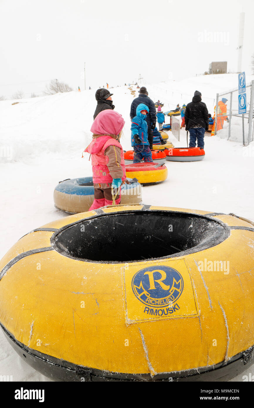 A queue of people with rubber rings waiting for the cable lift to go sliding in Rimouski Parc Beausejour, Quebec, Canada Stock Photo