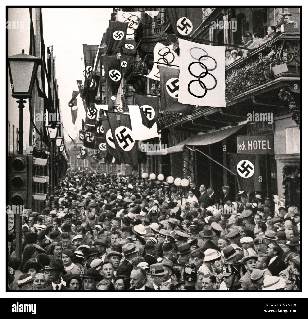 Nazi Olympic Games 1936 Berlin Street Crowds celebrations with Swastikas & The Olympic Rings Flags. Vintage B&W image of a crowded street in Berlin with Swastikas and Olympic flags flying, celebrating the 1936 Olympics in Berlin Germany, under the government controlled Nazi Party. (National Socialist German Workers Party). These Olympic Games offered a unique view into Germany and the Nazi movement that had taken control of the country. Stock Photo