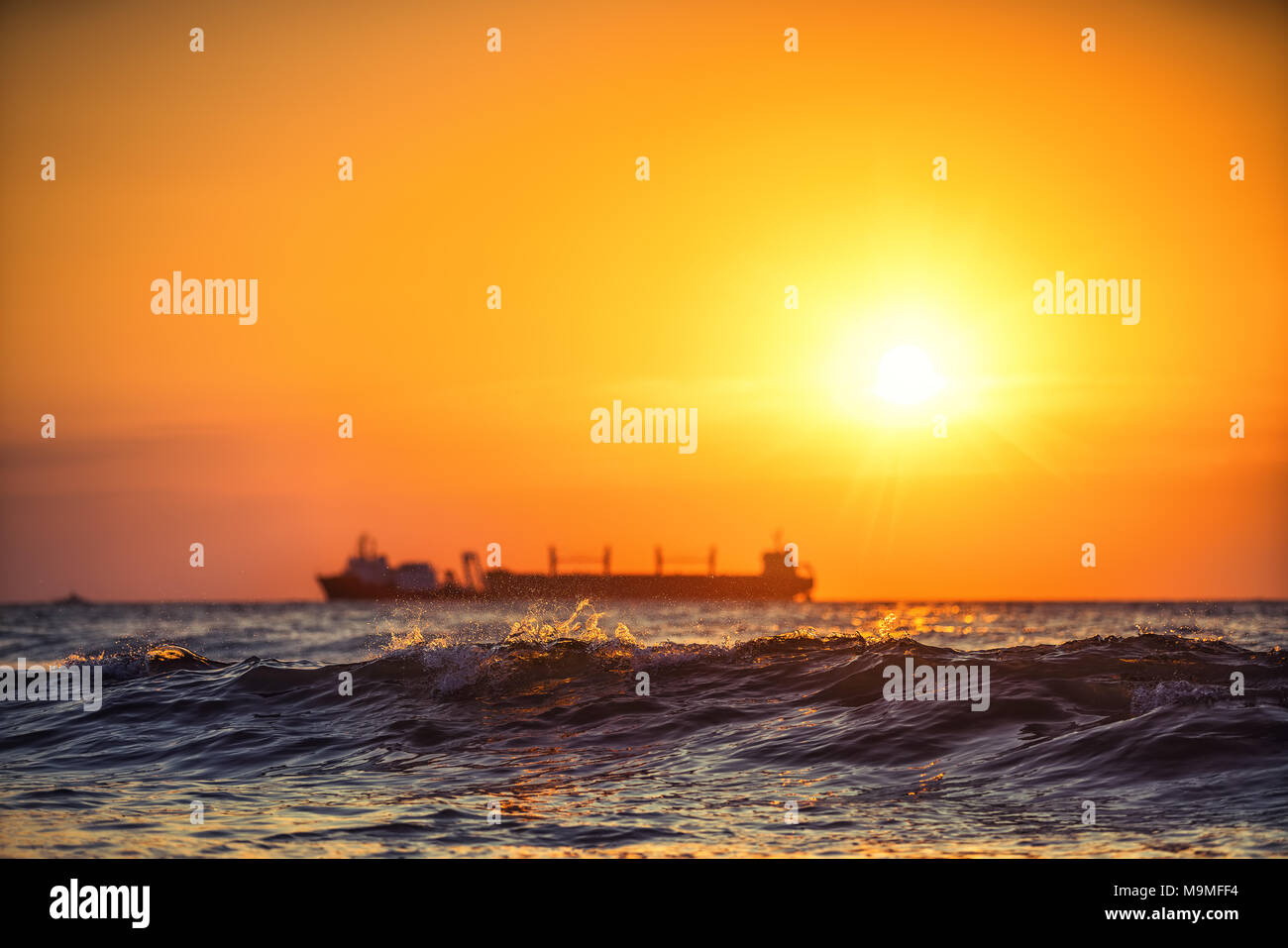 Sun setting at the sea with sailing cargo ship, sunrise. Transportation ...