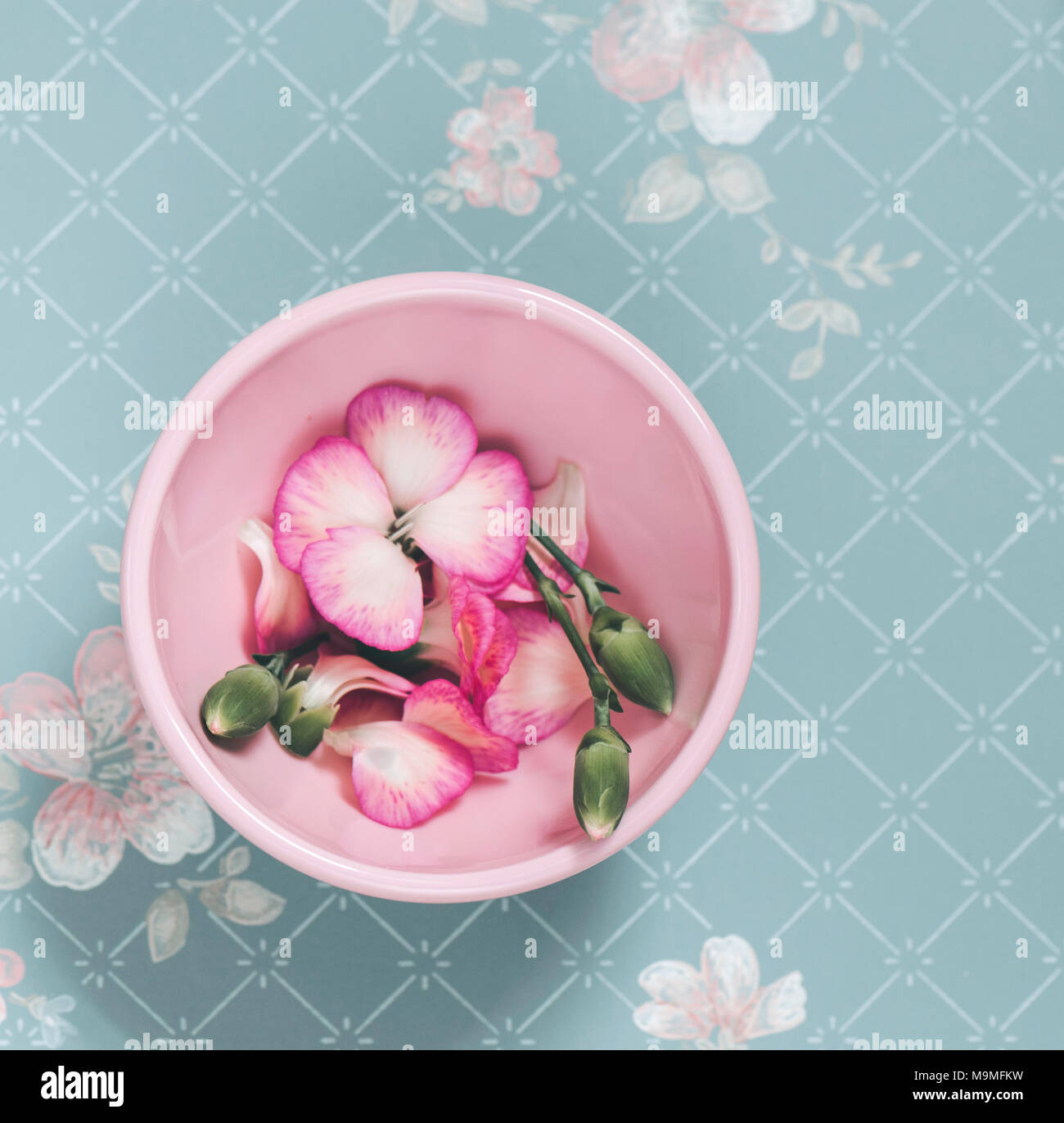 Pink bowl with flowers on a faded floral background Stock Photo