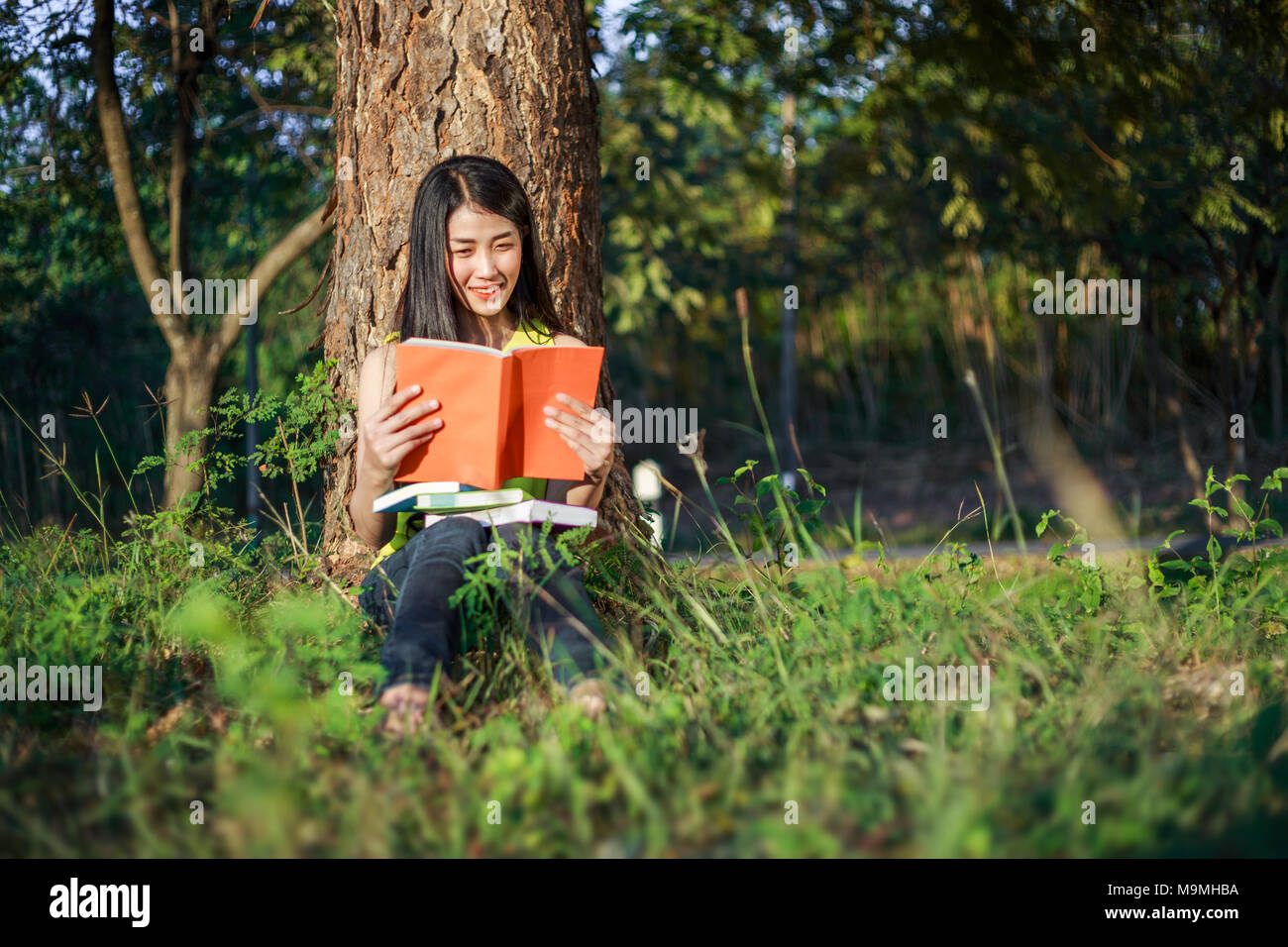 young woman sitting and reading a book in the park Stock Photo - Alamy