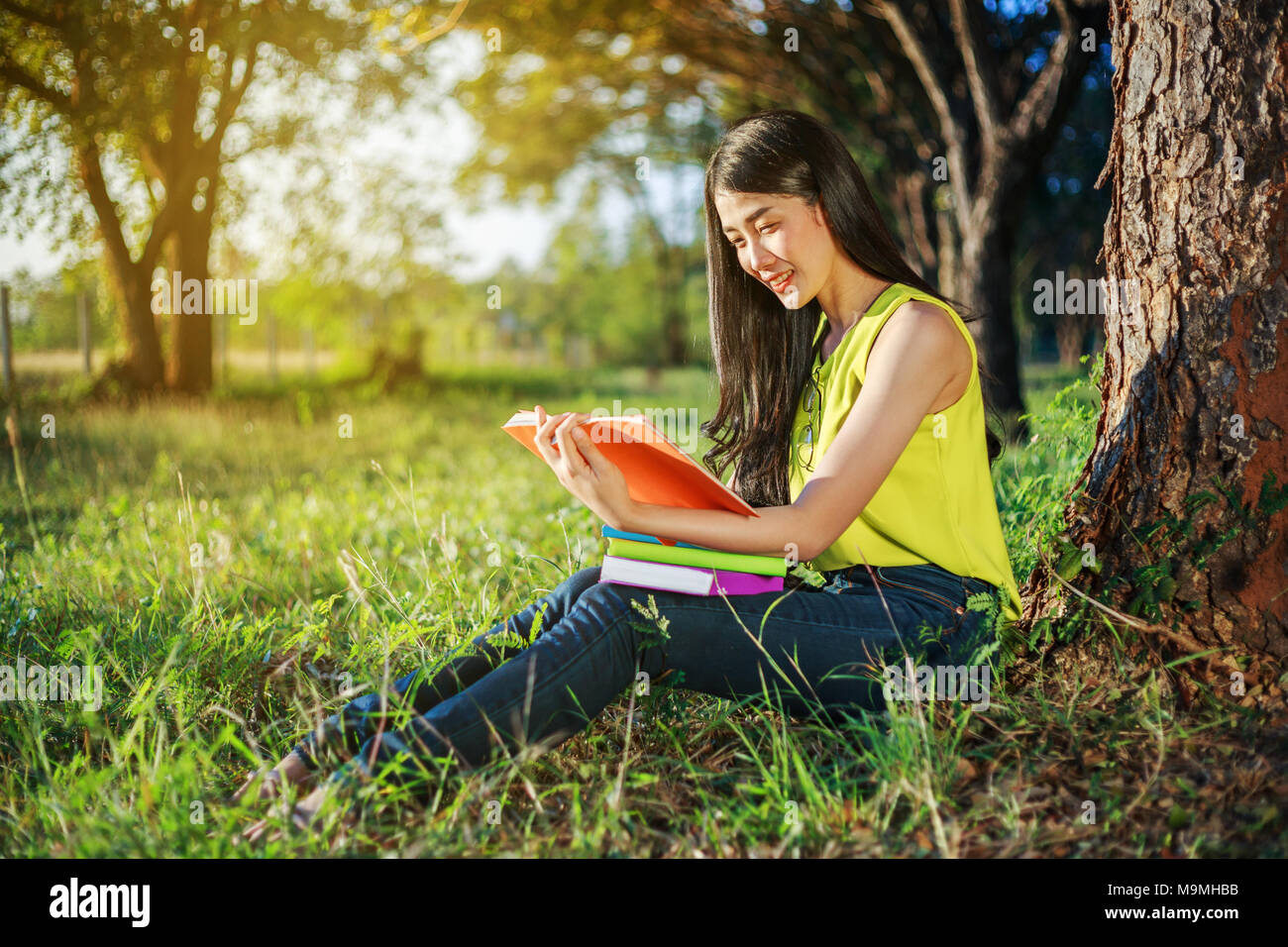 young woman sitting and reading a book in the park Stock Photo - Alamy