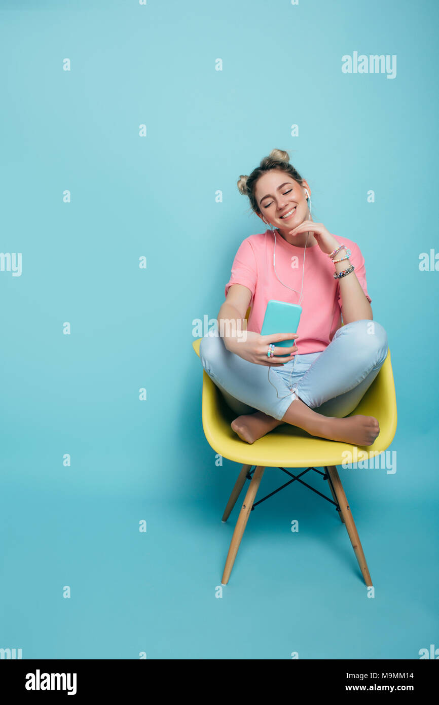woman sitting on a chair with crossed legs and listening to music Stock Photo