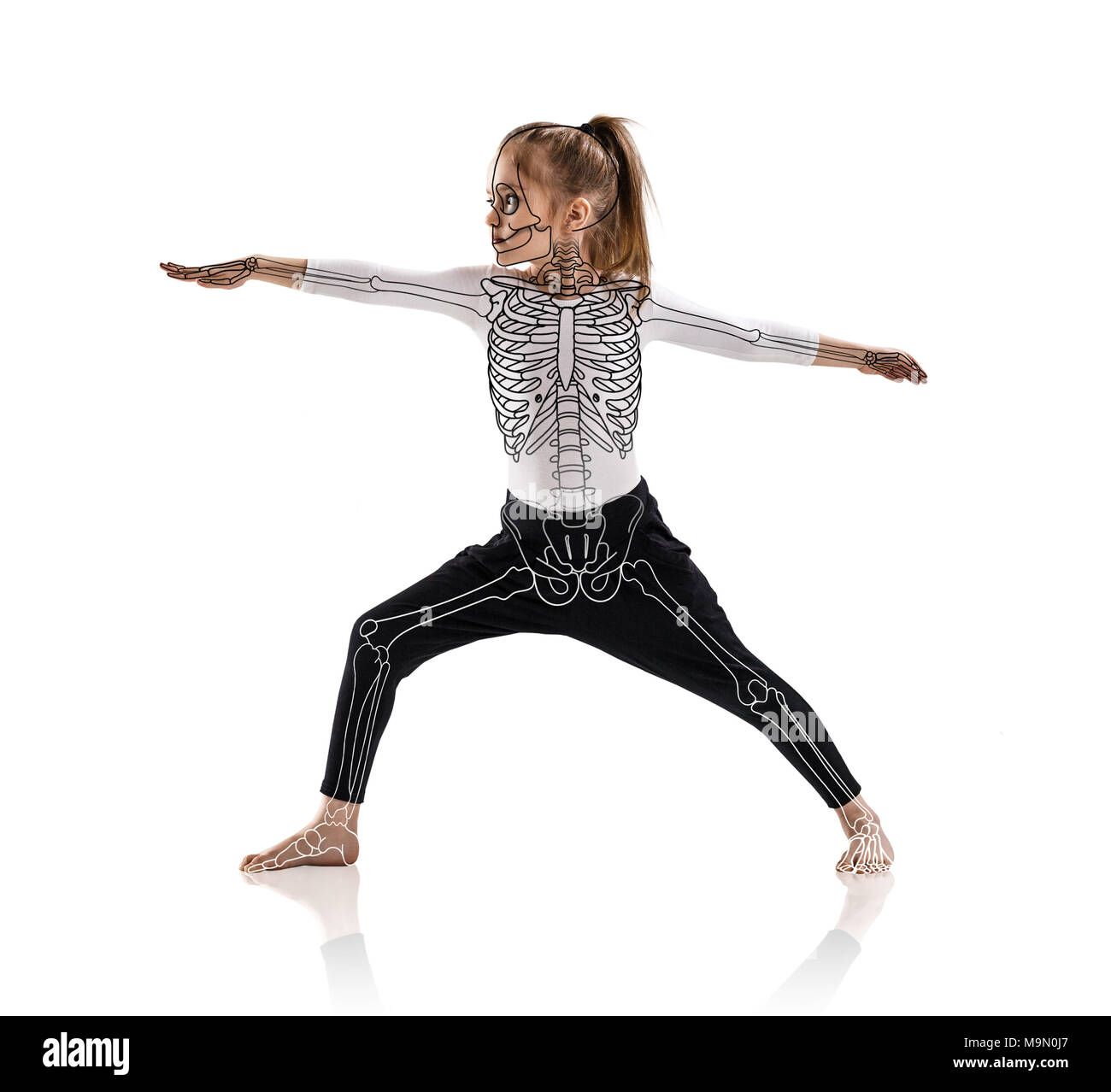 Little girl in a yoga pose with drawing skeleton. Stock Photo