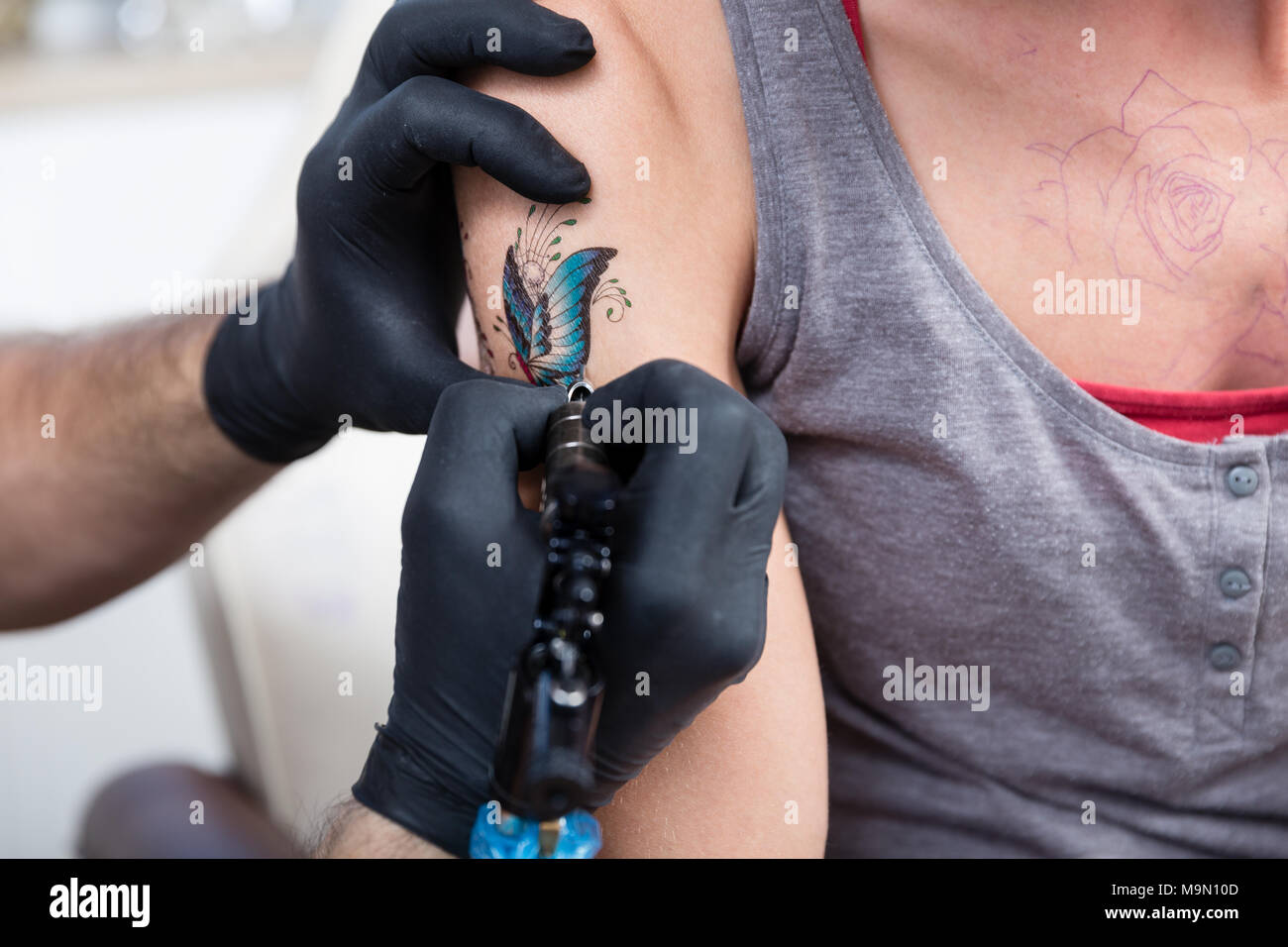 Hands of a cautious artist wrapping with dry plastic the new tattoo Stock Photo