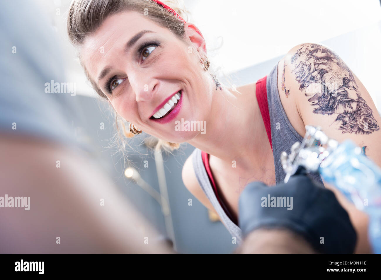 Cheerful woman smiling with confidence in a modern tattoo studio Stock Photo