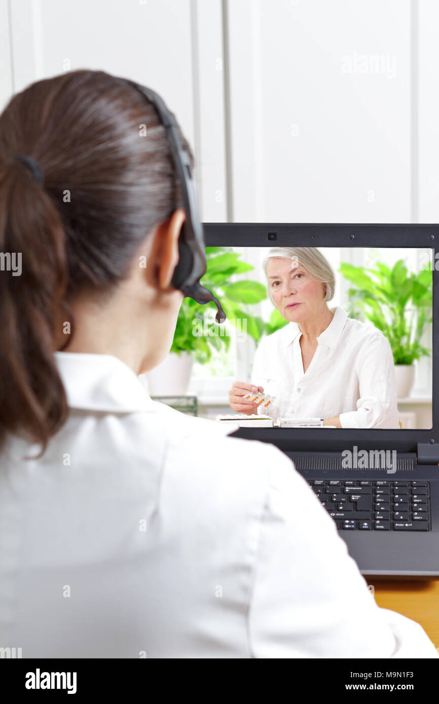 Female doctor of geriatrics with headset in front of her laptop during a video call with an old patient about her prescribed drugs, digital health Stock Photo