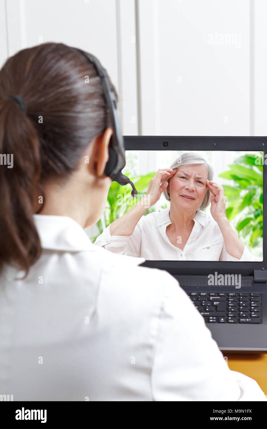 Female doctor with headset in front of her laptop during a video call with a fibromyalgia patient having sleeping trouble and headaches. Stock Photo