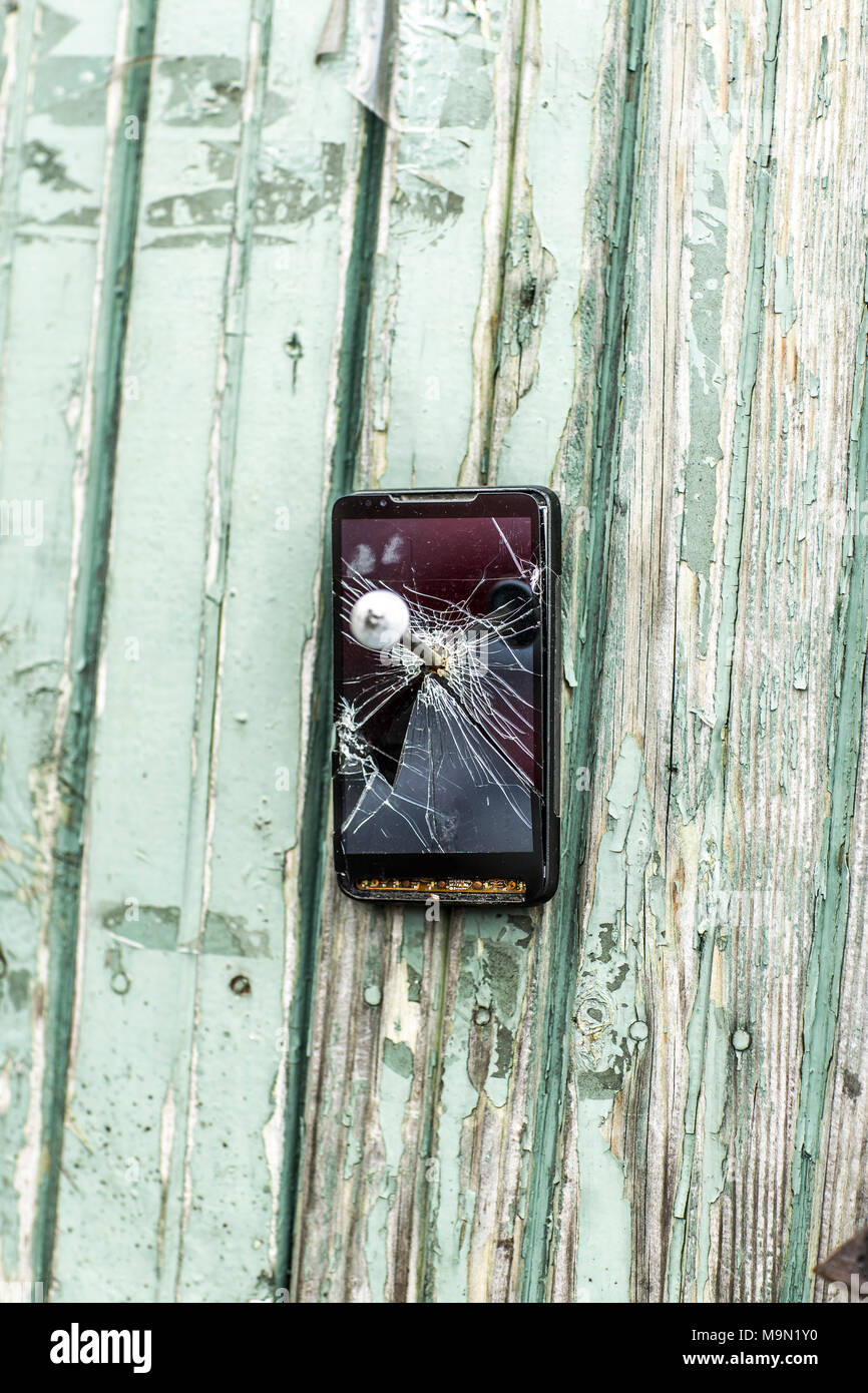 concept of obsolete technology:mobile phone nailed to the fence a large nail Stock Photo