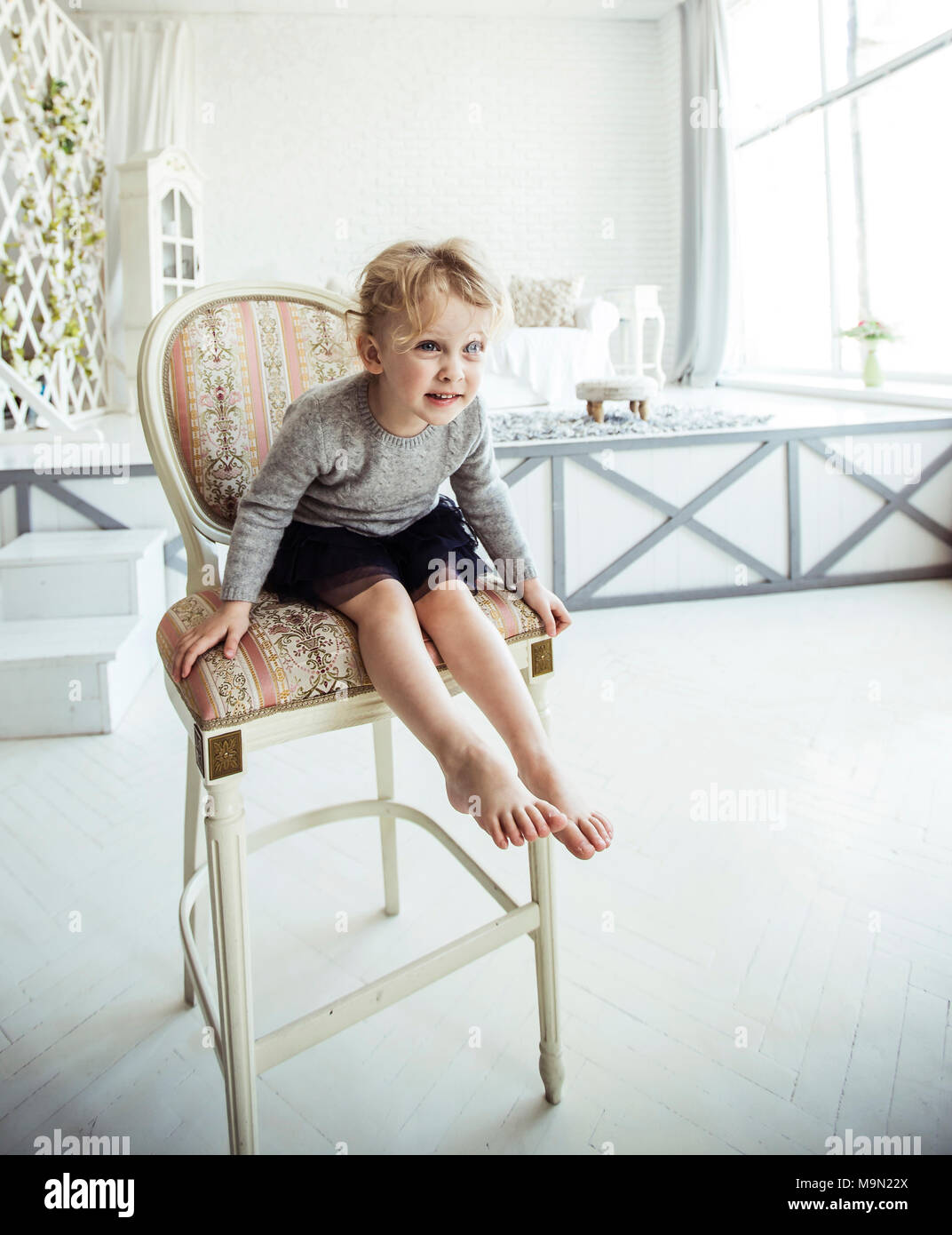 portrait of a happy five year old girl sitting on a chair in the ...