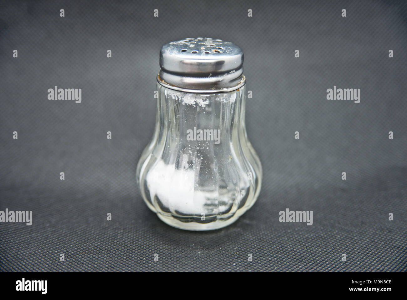 Ground salt and pepper shakers on a polished wood surface with light from a  window illuminating the table; rustic dining table with glass shakers Stock  Photo - Alamy