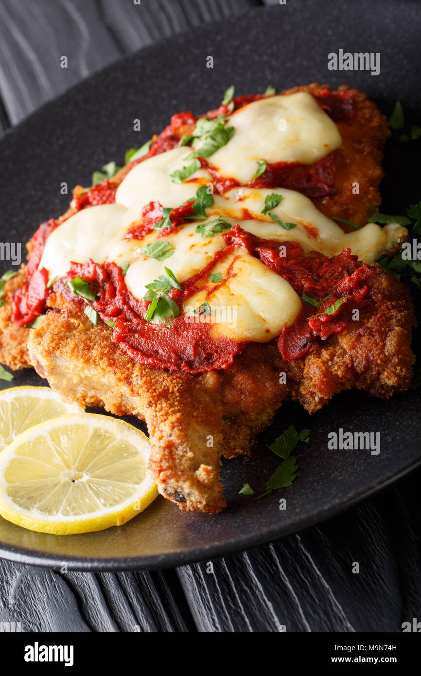Veal Milanesa Napolitana with mozzarella cheese and tomato sauce close-up on a plate on a table. vertical Stock Photo
