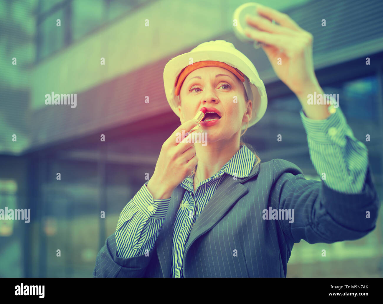 Employee woman in suit using lipstik and standing in helmet Stock Photo ...