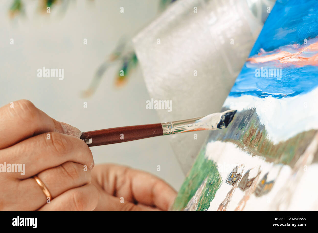 artist paints a picture of oil paint brush in hand with palette closeup ...