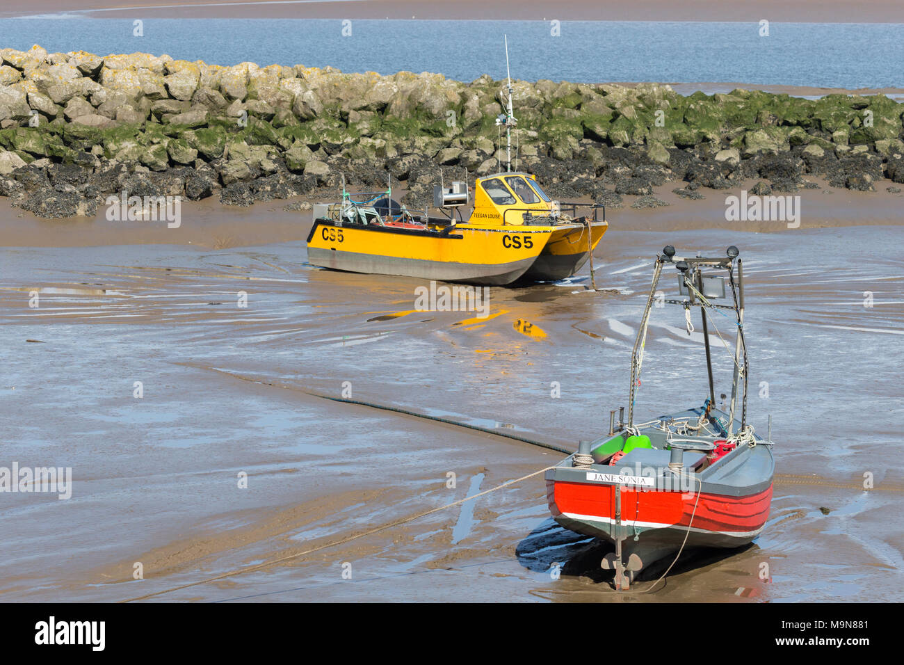 Two small inshore fishing boats aground and waiting for the tide at Morecambe, England, UK Stock Photo
