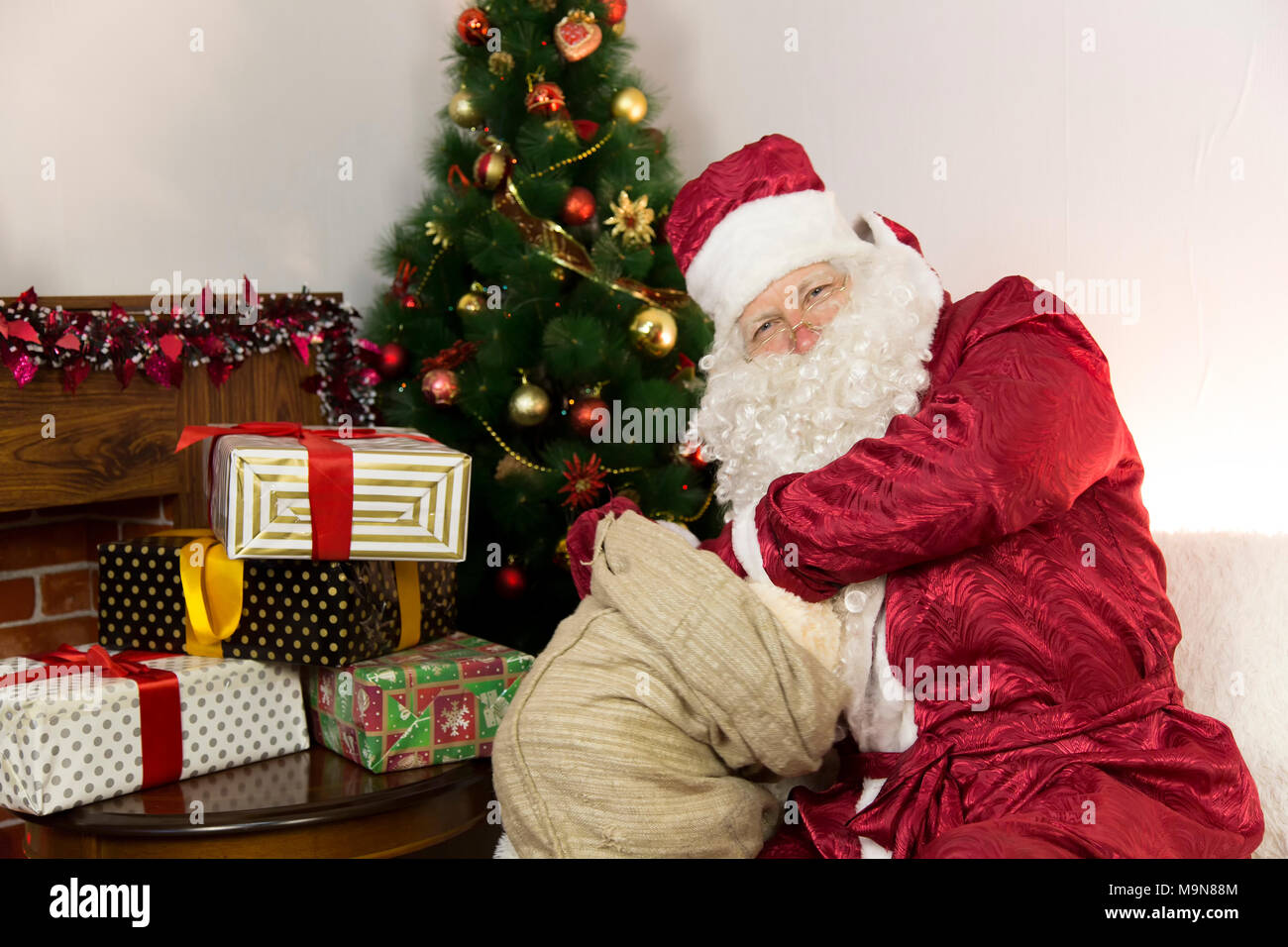 Merry Santa Claus gets a gift from a big gray bag - a soft toy Stock ...