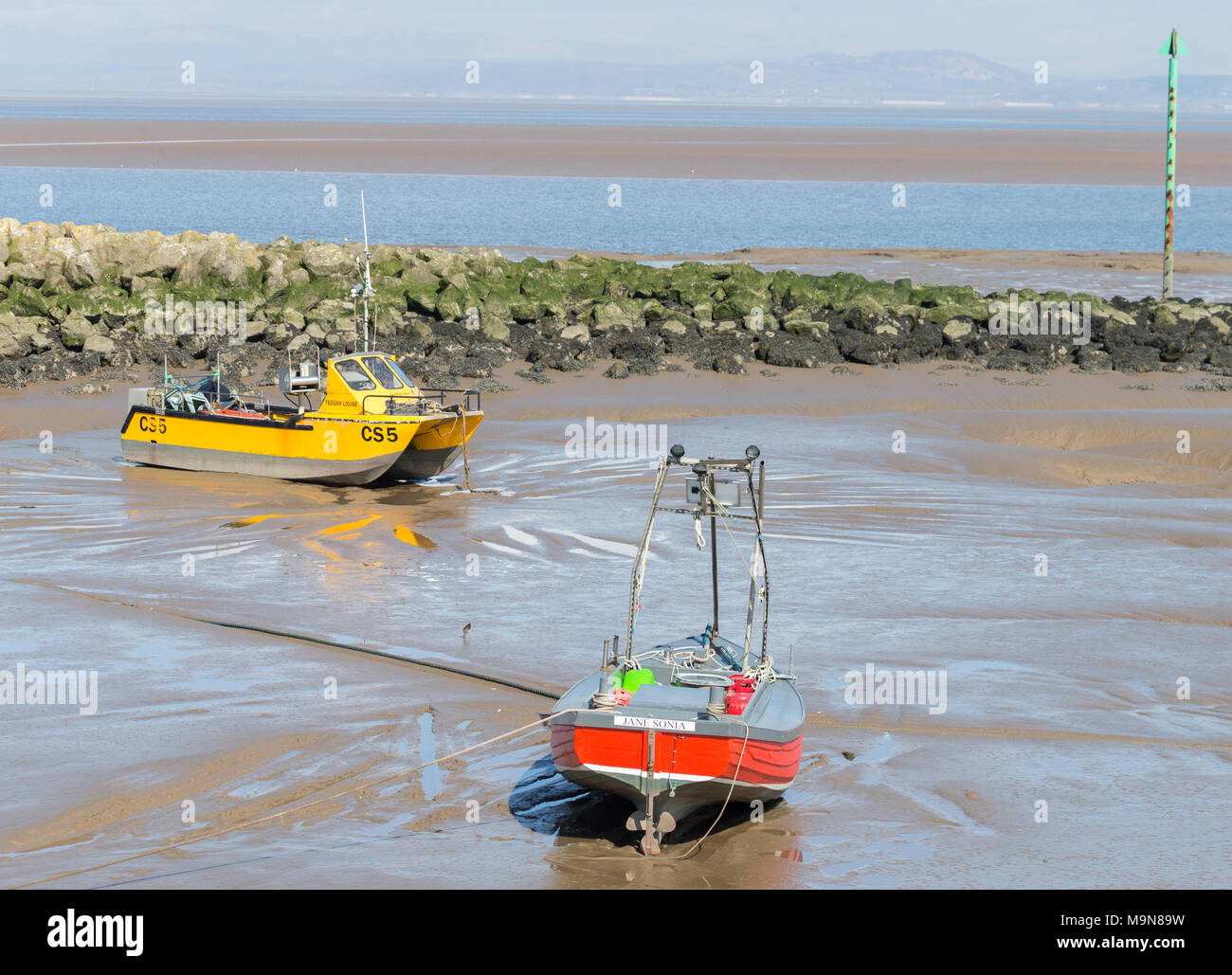 Two small inshore fishing boats aground and waiting for the tide at Morecambe, England, UK Stock Photo
